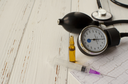 Apparatus for measuring the pressure, cardiogram, syringe, ampoule, pills on white wooden background, copy spaceの写真素材