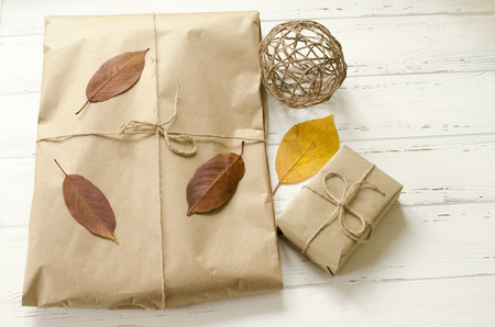 Gifts packaged in craft paper and  dry autumn leavesの写真素材