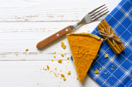 Pumpkin  pie, cinnamon sticks, autumn dry leaves on white wooden tablの写真素材