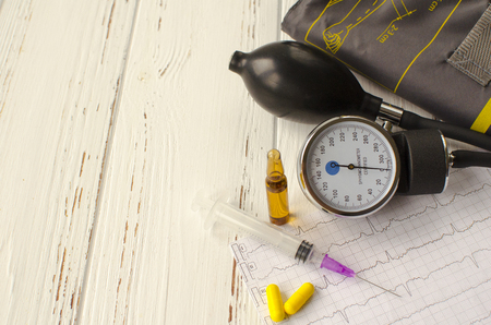 Apparatus for measuring the pressure, cardiogram, syringe, ampoule, pills and dry autumn leaf on white wooden backgroundの写真素材