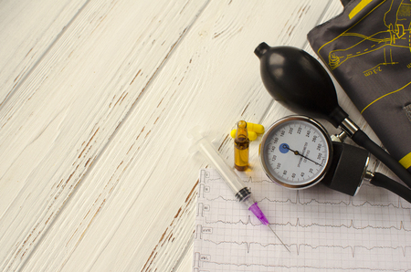 Apparatus for measuring the pressure, cardiogram, syringe, ampoule, pills on white wooden background, copy spaceの写真素材