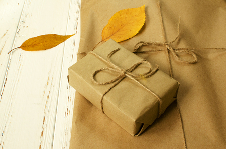 Gifts packaged in craft paper and  dry autumn leavesの写真素材
