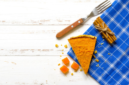 Pumpkin  pie, cinnamon sticks, autumn dry leaves on white wooden tableの写真素材