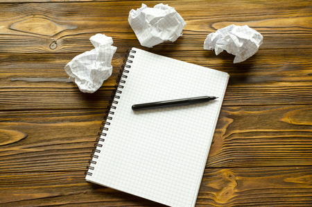 Notepad, pen and crumpled sheets on a wooden tableの写真素材