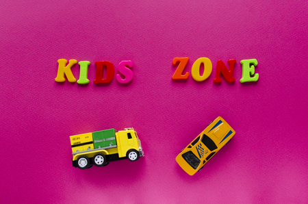 words "kids zone" with toy cars on pink backgroundの写真素材