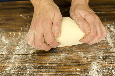 Hands knead the dough on wooden backgroundの写真素材
