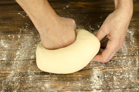 Hands knead the dough on wooden backgroundの写真素材