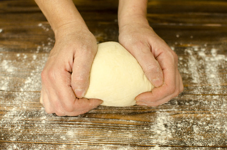 Hands knead the dough on wooden backgroundの写真素材