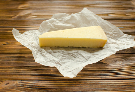 Parmesan cheese on  parchment paper on wooden backgroundの写真素材