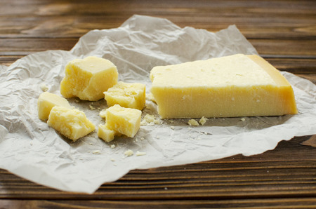 Parmesan cheese on  parchment paper on wooden backgroundの写真素材