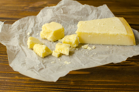 Parmesan cheese on  parchment paper on wooden backgroundの写真素材