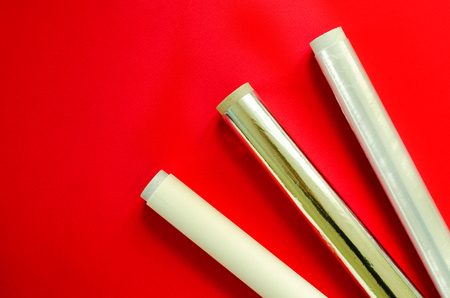 Plastic wrap, aluminum foil, parchment paper on red backgroundの写真素材