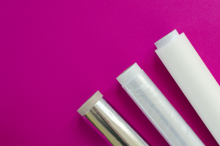 Plastic wrap, aluminum foil, parchment paper on pink backgroundの写真素材