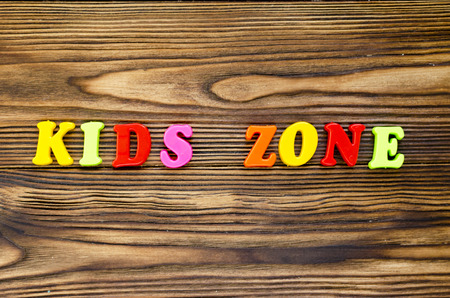 text "kids zone"  of plastic magnetic letters on wooden backgroundの写真素材