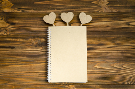 kraft paper notepad with hearts on wooden table. copy spaceの写真素材