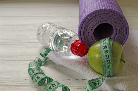 Two dumbbells, bottle of water, green apple, centimeter on white wooden background with space  for textの写真素材