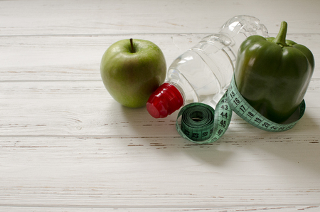 bottle of water, green apple and pepper, centimeter on white wooden background with space  for textの写真素材