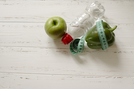 bottle of water, green apple and pepper, centimeter on white wooden background with space  for textの写真素材