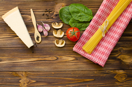 Italian food ingredients: pasta, tomato, spinach, pepper, porcini on wooden backgroundの写真素材
