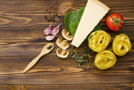Italian food ingredients: pasta, tomato, spinach, pepper, porcini on wooden backgroundの写真素材