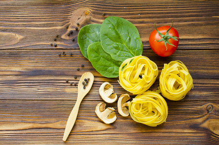 Italian food ingredients: pasta, tomato, spinach, pepper, porcini on wooden backgroundの写真素材