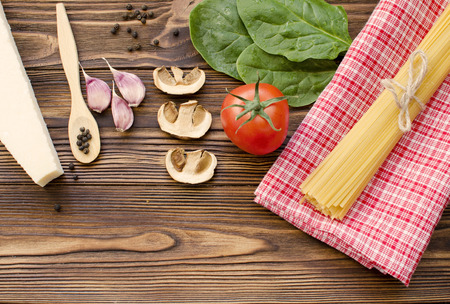 Italian food ingredients: pasta, tomato, spinach, pepper, porcini on wooden backgroundの写真素材