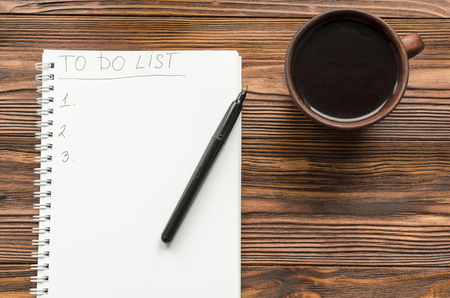 notepade with written phrase "to do list" and cup of coffee on wooden tableの写真素材