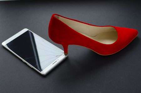 red shoes and broken phone on gray backgroundの写真素材