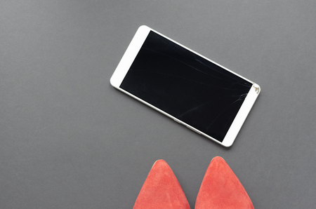 red shoes and broken phone on gray backgroundの写真素材
