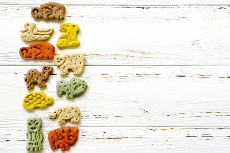 Delicious chewing colored bones and zoological biscuits  for dogs with different tastes on white wooden backgroundの写真素材