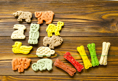 Delicious chewing colored bones and zoological biscuits  for dogs with different tastes on wooden backgroundの写真素材