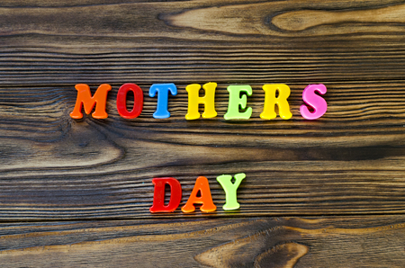 text "mothers day" of plastic colored magnetic letters on wooden backgroundの写真素材