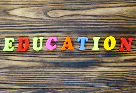 text "education" of plastic colored magnetic letters on wooden backgroundの写真素材