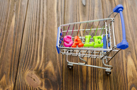 word "sale" and empty shopping cart on wooden backgroundの写真素材