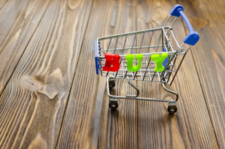 word "buy" and empty shopping cart on wooden backgroundの写真素材