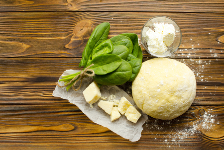 Dough, spinach,parmesan, ricotta on wooden background are ready for cooking ravioliの写真素材