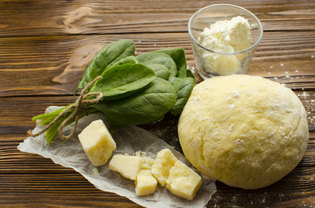 Dough, spinach,parmesan, ricotta on wooden background are ready for cooking ravioliの写真素材