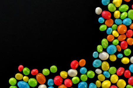 Multicolored candy on black background with space for textの写真素材