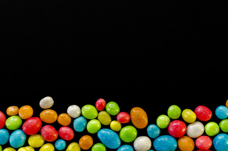 Multicolored candy on black background with space for textの写真素材
