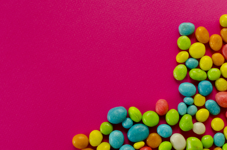 Multicolored candy on pink background with space for textの写真素材