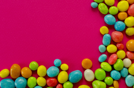 Multicolored candy on pink background with space for textの写真素材
