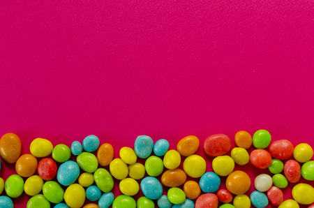 Multicolored candy on pink background with space for textの写真素材