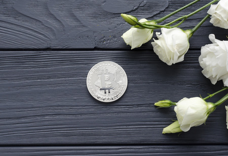 silver bitcoin and eustoma flowers on grey wooden backgroundの写真素材