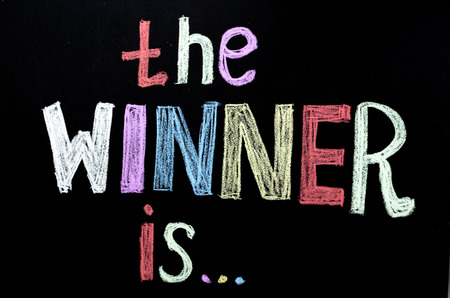 colored hand written text 'the winner is ' on chalkboardの写真素材