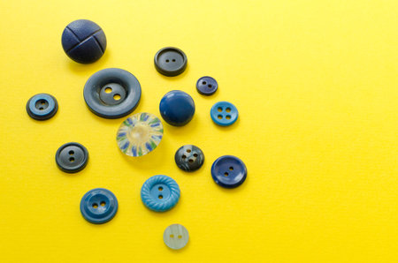 Blue plastic buttons on yellow paper background