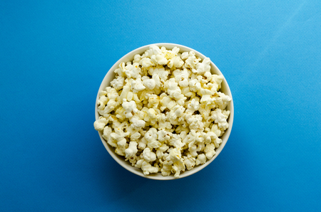 plate with popcorn on blue paper backgroundの写真素材