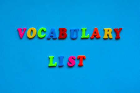 text vocabulary list from plastic colored letters on blue paper backgroundの写真素材