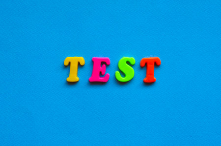 text test from plastic colored letters on blue paper backgroundの写真素材