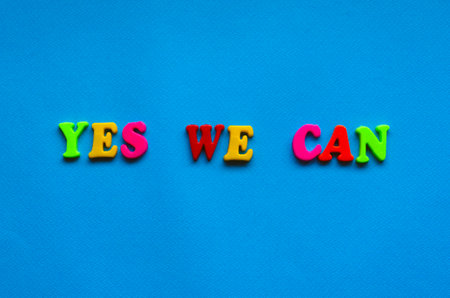 text yes we can from plastic colored letters on blue paper backgroundの写真素材