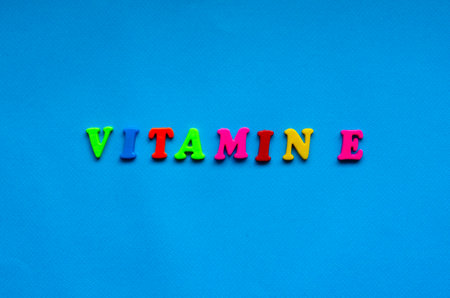 text vitamin e from plastic colored letters on blue paper backgroundの写真素材
